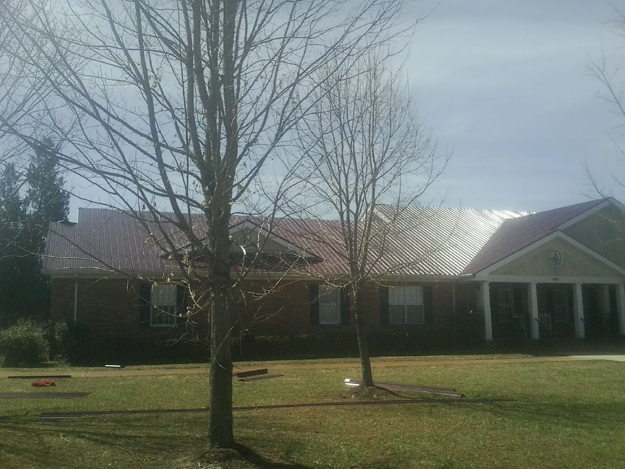 Red metal roof on a brick building seen from the front lawn in Utica